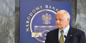 Adam Glapiński na konferencji NBP, w tle wykres stóp procentowych i rata kredytu.